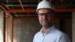 © Ivan - A construction manager stands confidently at a work site, wearing a hard hat and glasses. His expression reflects focus and professionalism, highlighting ongoing construction efforts