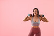 © New Africa - Woman in gym clothes exercising with dumbbells on pink background, space for text