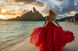 © Atlantis - Femme en robe rouge sur une plage à Bora