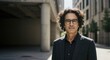 © IbragimovN - Confident businessman in urban setting with curly hair and glasses