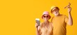 © Pixel-Shot - Mature couple of tourists with passports and wooden airplane on yellow background with space for text