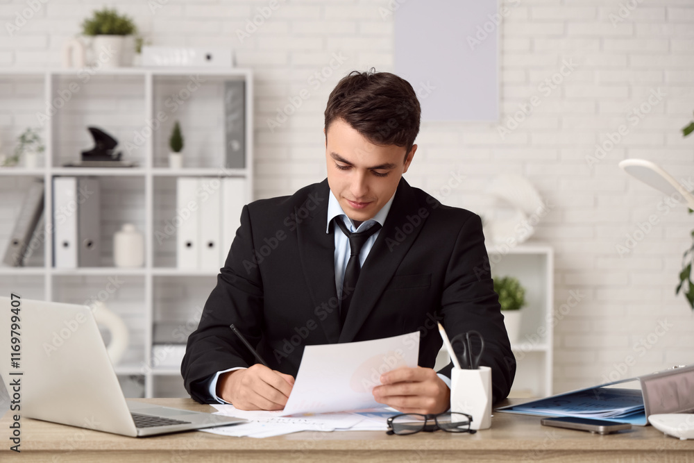 Male economist working with diagrams at table in office