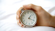 © 沈军 贡 - Close-up of a woman's hand turning off an alarm clock in bed, against a white background