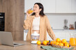 © Pixel-Shot - Young woman drinking sweet orange juice in kitchen