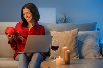 Poster - Young woman with gift box having online date on sofa at home in evening