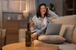 © Pixel-Shot - Young woman with wine having online date on sofa at home in evening