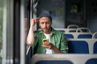 © DimaBerlin - Man absorbed in music and podcasts through earbuds, traveling to work on train with smartphone in hand. Audio engagement and getting away, commuter life, solo travel and tourism, modern technology