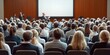 © Planetz - Large Group of People Attending Presentation in Auditorium with Presenter on Stage Engaging Audience with Visuals and Insights for Learning and Inspiration