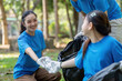 © Natee Meepian - Family volunteers collecting garbage in community park nature cleanup event outdoor family activity engaging community efforts
