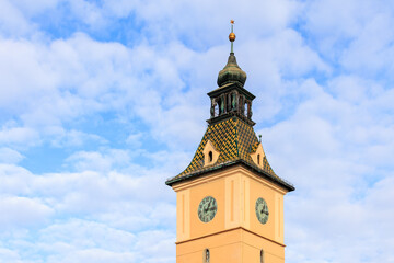 A tall clock tower with a gold roof and a weather vane on top