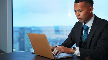 Poster - A male business person working on a laptop in a high-rise office