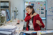 © Phimwilai - Young professional woman massaging her neck, experiencing discomfort and stiffness after prolonged computer work, highlighting the physical strain of office jobs