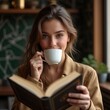 © Caspernik - Young Woman Holding Coffee, Drinking And Reading A Book