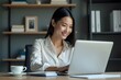© Paull - Asian young owner business woman working online, checking mail on laptop organizing working process in office.
