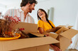 © oneinchpunch - Happy young couple relocating in a new apartment. Young woman and man working and arranging the new property they just bought. Moving stuff and boxes together.