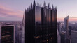 © Qaiser - A gothic-inspired skyscraper rises above the city, its dark, reflective glass panels arranged in vertical sections.