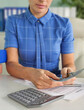 © Nadzeya - Woman counting cash and using calculator at desk with financial documents