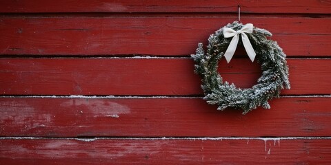 A festive Christmas wreath adorned with a bow hangs on a rustic red wooden wall, embodying holiday warmth and tradition.