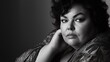 © Oldcorporal - Stylish plus-size hispanic woman in elegant attire posing confidently in black and white portrait