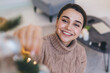 © BullRun - Positive woman trimming New Year tree with decorations at home