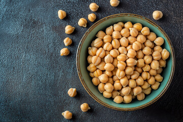 Wall Mural - Top view of fresh chickpeas in a bowl on a dark textured surface, showcasing healthy ingredients.