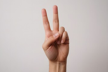 A Close-Up Shot of a Hand Showing the Number Two, Peace Sign, or Victory Gesture Against a Neutral Background