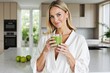 © Jasper - Green Smoothie Glow: A beautiful woman radiates health and vitality, holding a refreshing green smoothie in a modern kitchen.  She embodies a healthy lifestyle and a commitment to wellness.