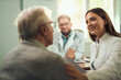 © Goran - Happy female nurse talking to her senior patient at doctor's office.