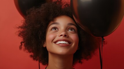 Wall Mural - A joyful woman smiles brightly while holding black balloons, dressed in a stylish black turtleneck sweater, radiating elegance and cheerfulness.