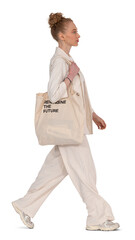 fashionable woman in a beige suit and carrying a tote bag walking in profile side towards the camera