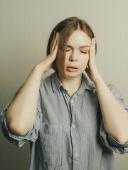 Canvas Print - A woman experiencing a migraine headache closes her eyes and holds her head, expressing discomfort fatigue.