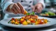 © we3_food - Close-up of chef's hands plating grilled salmon with mango salsa and basil.