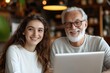 © GHM_STUDIO - Senior man and young woman smiling while using laptop