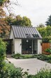 © gamespirit - Charming small modern house surrounded by lush greenery and a concrete path showcases contemporary architecture with a sloped metal roof and large windows