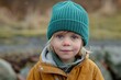 © juliars - Adorable young child with rosy cheeks wearing a knitted beanie and warm jacket, enjoying a day outdoors