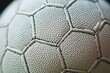 © agungcanva123 - Close-up of a white textured sports ball's hexagonal panels and stitching.