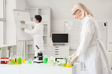 Sticker - Female chemist with flasks on table in laboratory