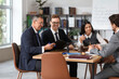 © Pixel-Shot - Group of lawyers working at table in office