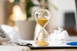 © Pixel-Shot - Hourglass on clipboard in office, closeup