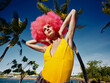 © SHOTPRIME STUDIO - Pinkhaired woman posing in front of palm trees on a hawaiian beach, with clear skies and ocean in the background, capturing a vibrant and tropical vacation vibe