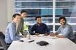 © fizkes - Happy multiethnic business colleagues sitting at large table in conference meeting room, looking away together, smiling, laughing, watching presentation, glad to see someone, enjoying cooperation