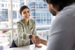 © fizkes - Happy beautiful young Indian businesswoman shaking hands with male partner over meeting table, giving greeting handshake to business colleague after negotiation, job interview, smiling, laughing