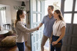 © fizkes - Successful female real estate insurance agent and couple of customers shaking hands at home. Homeowners, property buyers, renters consulting realtor in apartment, giving handshake
