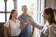 © fizkes - Positive landlady, rental broker, real estate agent woman giving key from new home to happy couple of new homeowners, tenants, house buyers. Renters meeting with realtor