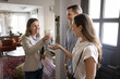 © fizkes - Happy successful realtor giving key to new homeowners after buying apartment, house to positive young couple. Husband and wife renting furnished accommodation