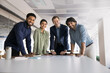 © fizkes - Multiethnic team of four happy ambitious young colleagues standing at workplace, leaning on meeting table, looking at camera, smiling, laughing, posing for corporate diversity portrait