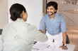 © fizkes - Happy confident young Indian businessman shaking hands with female business partner, colleague after signing contract, agreement, successful negotiation, giving handshake over table