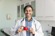 © fizkes - Happy cardiologist doctor man showing red toy heart at camera, holding symbol of healthy heart, promoting medical examination, cardiac disease early prevention