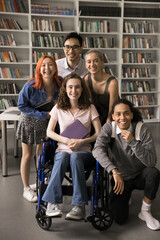 Wall Mural - Inclusion and diversity. Vertical shot happy diverse polyethnic students group posing for portrait. Smiling teen female on wheelchair look at camera together with friendly supportive mates at library