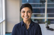 © fizkes - Happy beautiful Indian businesswoman looking at camera with perfect toothy smile, posing for front head shot successful professional portrait, standing in office space alone